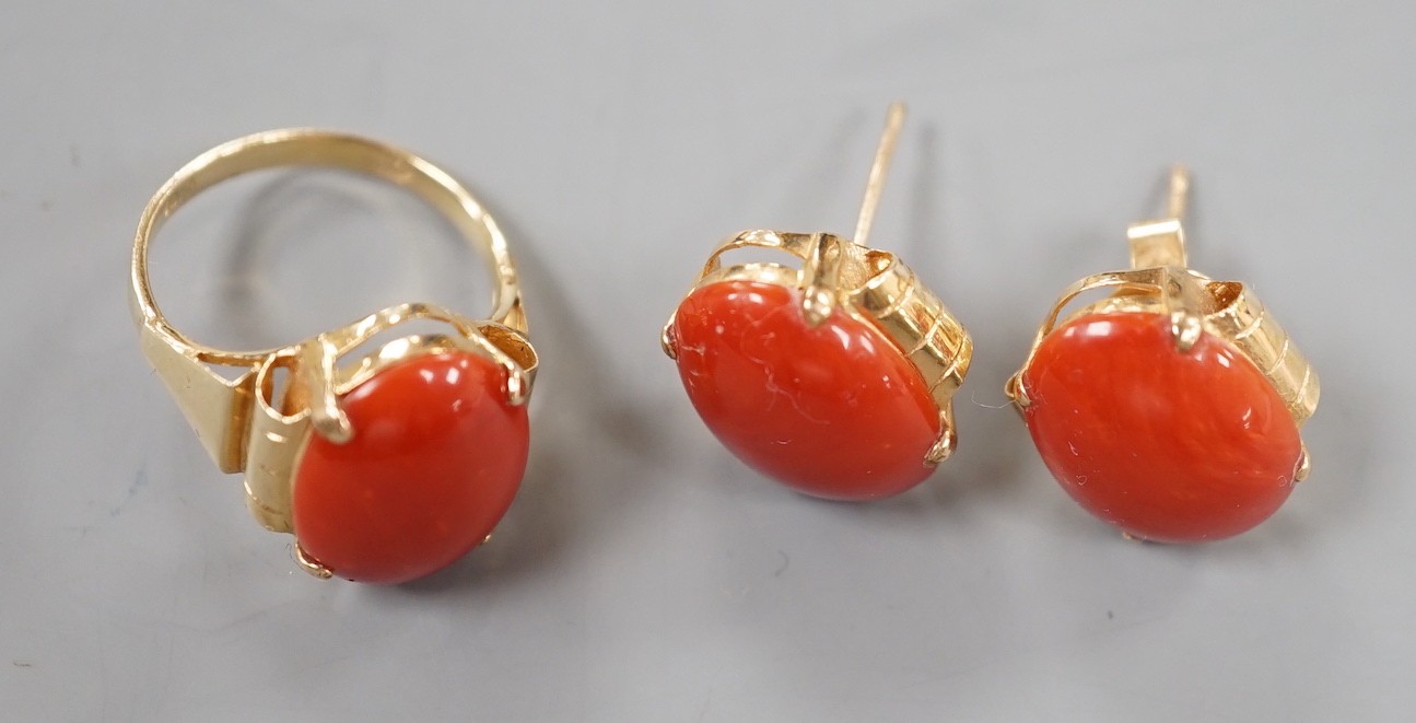 A 14k yellow metal and cabochon coral set oval ring, size N and a pair of matching earrings, lacking one butterfly, gross weight 11.5 grams.